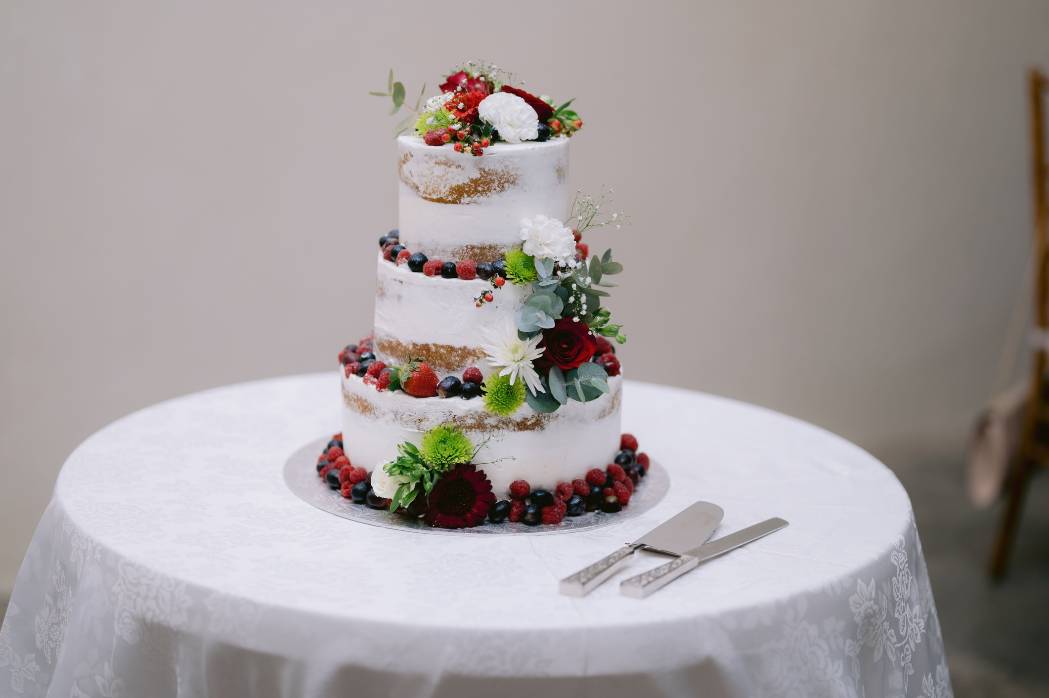 Die Torte, bestehend aus drei Etagen, die mit weißem Zuckerguss überzogen und mit frischen Blumen dekoriert ist.
