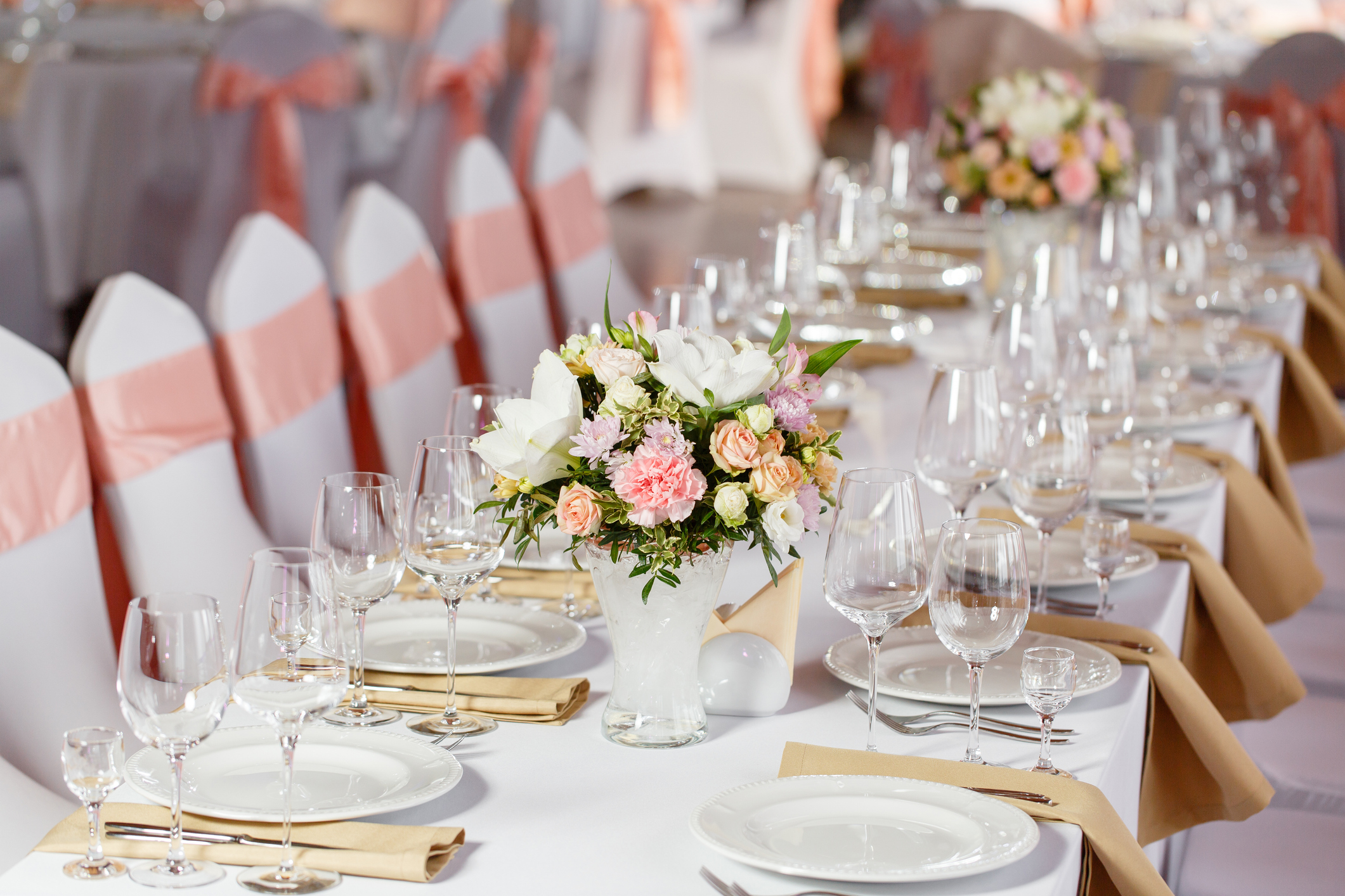 Der gedeckte Tisch mit weißen Tischdecken, weißen Stühlen, weißen Tellern, silbernem Besteck, Weingläsern und einem großen Blumenstrauß in der Mitte.
